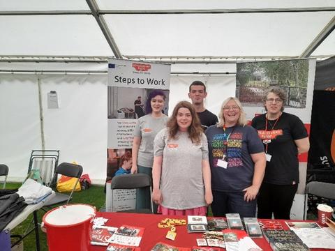 5 people on exhibition stall at Disability Awareness Day with banner saying 'Steps to Work' behind them
