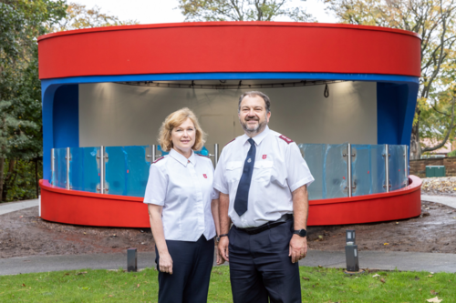 Two people in Salvation Army uniforms stand in front of a new bandstand which is under construction at Strawberry Field