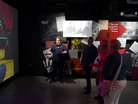 People stand inside exhibition space about John Lennon
