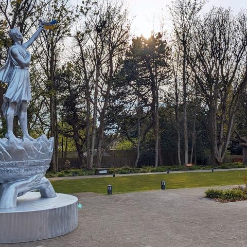 Monument depicting a person holding aloft a book, a dove and Ukrainian flag stands in the garden at Strawberry Field  